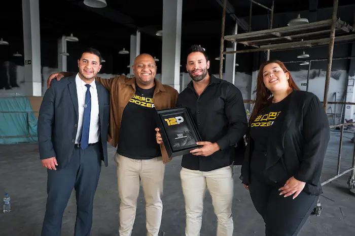 Equipe da 12P e cliente posando com placa de reconhecimento